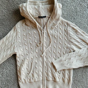 Stickad luvtröja Brandy💗Melville - Såå fin stickad tröja från Brandy. 60% bomull, 40% akryl. Beige, kabelstickad, luva, fickor & dragkedja. Endast testad kortare stund, så i nyskick! 150:- 