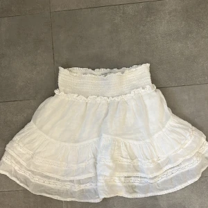 Vit neo noir kjol  - Jättefin vit volangkjol från neo noir. Storleken är S men pga stretchig midja passar den troligen även M och XS. Har inga defekter och jättebra skick. Säljer pga att den aldrig används.   