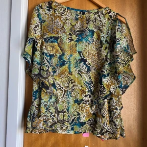 Blus  - Ny, aldrig använd. Står varken storlek eller märke men gissar att den passar allt från Xs-M beroende på hur man vill att den ska sitta. Jättefina volanger på sidorna av blusen. Tunt material perfekt för sommaren