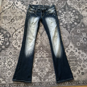 Jeans -00tal populära blue queen // 34 - Låga i midjan, trendiga!  Paljetter & broderier. Dock defekt. Knapp saknas men går lätt att fixa hemma eller hos en skräddare.  Bra skick för övrigt!  Storlek 34  Mått vid midjan 70cm  Total längd 97,5cm från midjan och ned.  Innermått lår: 81cm  