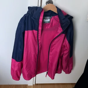 Rosa och mörk blå jacka  - Jackan är vind och vatten tät och den håller värmen på hösten och våren   Stora fickor som rymmer mycket . Kan sänka