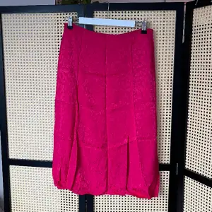 Otrolig rosa färg på denna kjol som slutar under knäna och har en slits framtill  100% viskos  Superfint skick utan anmärkningar utöver att den behöver strykas   Något stor i storleken, skulle säga 36-38