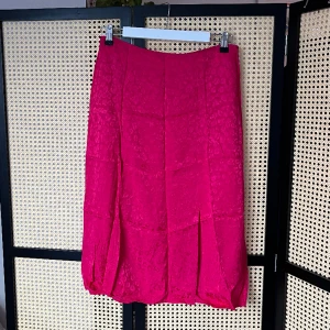 Knälång kjol med slits  - Otrolig rosa färg på denna kjol som slutar under knäna och har en slits framtill  100% viskos  Superfint skick utan anmärkningar utöver att den behöver strykas   Något stor i storleken, skulle säga 36-38