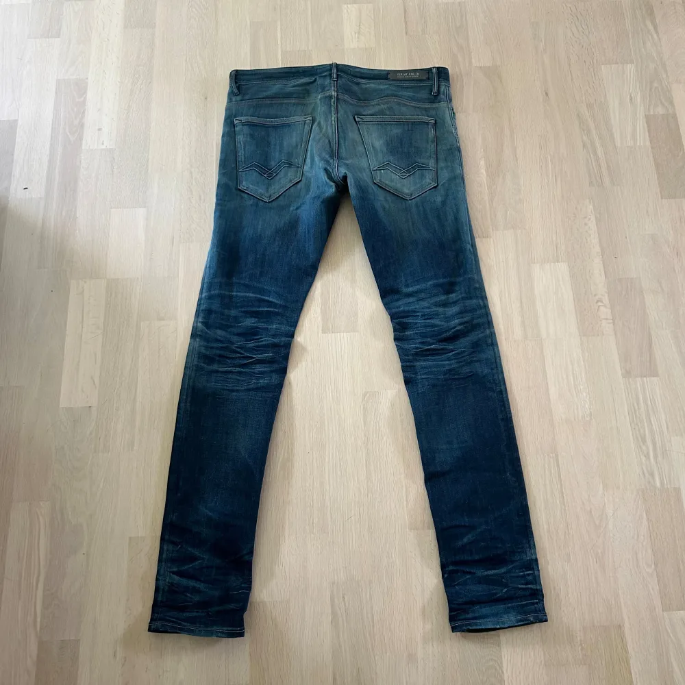 Ett par blå jeans från Replay. Jeansen har en tapered passform och är tillverkade i denim. De har en klassisk femficksdesign med två bakfickor och tre framfickor. Jeansen har en knappgylf och är i bra skick skick.. Jeans & Byxor.