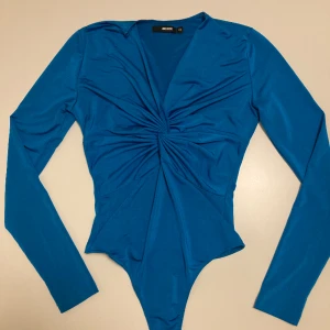 Superfin blå body - Jättefin blå body från Bik Bok, använd några gånger med litet slitage längst upp, se bild 2. Går att sy, annars är den i fint skick. Supermjukt material och väldigt smickrande. 