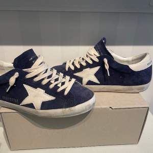 Hej! Säljer nu de mest eftertraktade Golden Goose skorna just nu! Vit stjärna och i navy colorway! Storleken är 40 men sitter väldigt stort då passar även 41-42. Allt OG finns! Nypris ligger på drygt 6000! Skorna har varit använda 5 gånger så nya ish