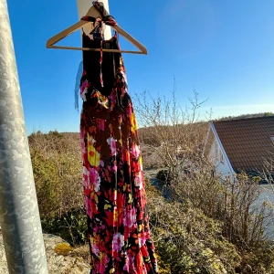 Färgglad blommig sommarklänning  - Klänningen är inte använd nu på några år men den är normal i storlek och lite stretch mellan bysten och midjan. Armlös klänning så man knyter bakom nacken och så är den lite bar på ryggen som man kan se på bilderna😊 material: polyester 