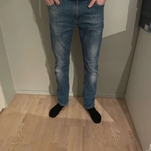 Nudie Jeans - Ett par snygga blåa nudie jeans i storlek 31/32, men passar också i waist 29. Har en liten defekt (se bild 3) men är ändå 8/10 skick. Modellen är runt 180. Nypris på dom här är runt 1600 och vårt pris är 349 kr! Hör av dig vid minsta fråga!