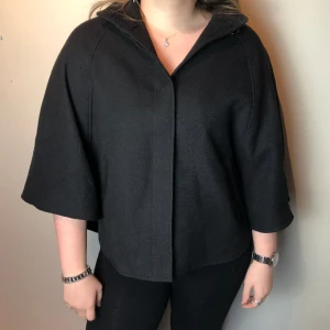 Svart ponchojacka - Drömmig ponchojacka som hänger så fint! Perfekta jackan!! Modellen bär vanligtvis S