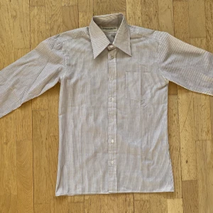 Randig skjorta - Fin röd, svart, vit randig skjorta i skönt material. Står storlek 16 i skjortan, men skulle säga att den sitter som xs, passar mig som är 160. I väldigt gott skick🌟