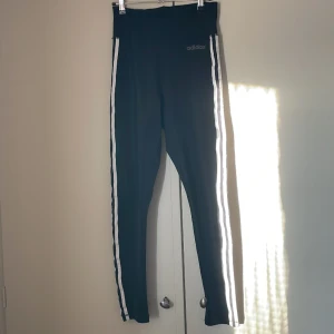 Träningstights - Träningstights från adidas med tre ränder på sidan. Skönt material och fint skick då det endast är använt ett fåtal gånger. Storlek XS men passar S bättre💗 Kan säljas tillsammans med adidasjackan(se min profil) för ett lägre pris☺️