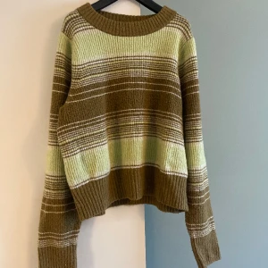 Stickad tröja  - Stickad tröja i storlek L. Grön-randig, köpt på Monik. Något längre ärmar än vanligt. Normal i storleken. 
