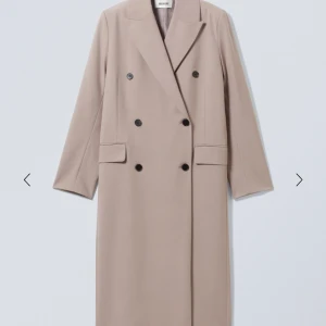 Kappa från Weekday, beige/grå, strl 34 - Ny vår/höstkappa från Weekday. Använd vid ett tillfälle. Yttertyg i 67% polyester, 33 % viscose. Foder i 100% polyester. Längd: 120 cm Inköpt för 1100kr på Weekday 2023.