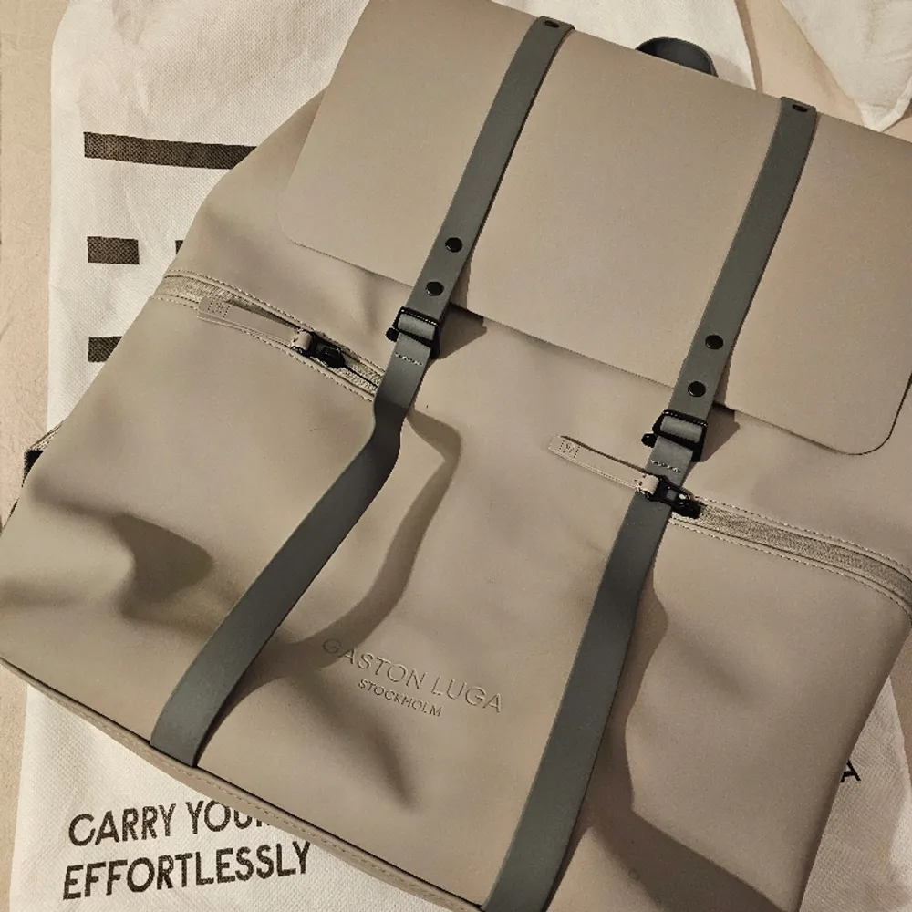 Nyskick Gaston Luga ryggsäck i färgen Taupe. Passar laptop från 11-16 tum. Smidigt till skolan/jobbet . Använd 2 gånger. Dustbag ingår. Nypris 1300kr . Väskor.