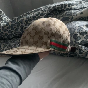 Gucci Keps äkta - Säljer min Gucci keps då den ej används längre. Kepsen är använd men är i bra skick och det finns en liten repa som ni kan se på kepsen men syns knappt. Kepsen är äkta och i storlek S.