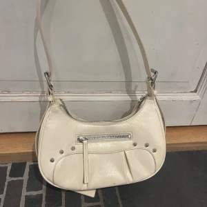 Vit handväska - Säljer denna fina vita handväska från Monki då jag har köpt en annan och ej är i behov av denna. Använd ett flertal gånger men är tvättad och fortfarande i bra skick!! Betalas via Swish och pris kan diskuteras!