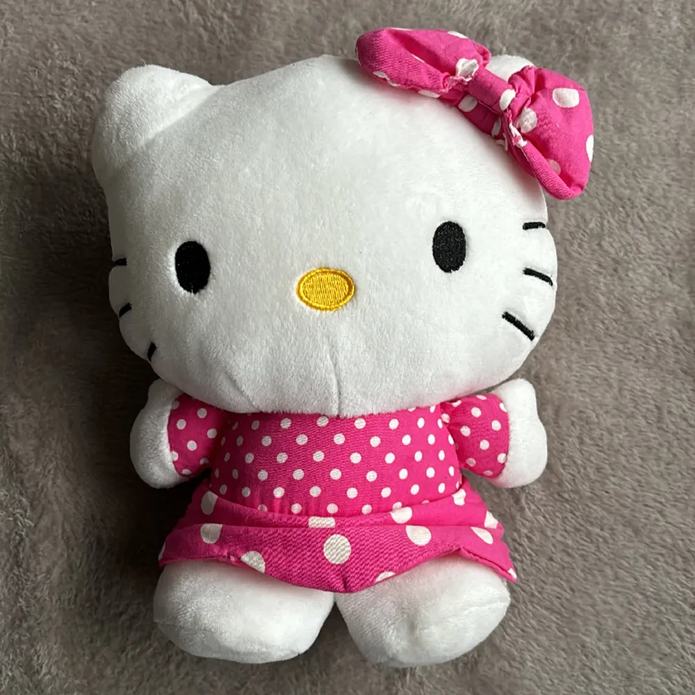 Söt Hello Kitty-väska utan axelrem och handtag. Dragkedja på baksidan, man får endast rum med något litet, se bild. Ca 25 cm hög. Fint skick. Väskor.