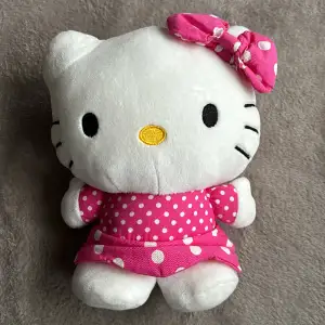 Söt Hello Kitty-väska utan axelrem och handtag. Dragkedja på baksidan, man får endast rum med något litet, se bild. Ca 25 cm hög. Fint skick