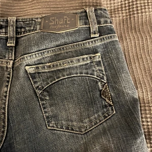 Lågmidjade jeans  - Supersnygga Lågmidjade jeans från shaft jeans. De är lite stora för mig som vanligen har xs-s så någon som har M hade kunnat ha dessa. Jag är 168 cm och de är för långa på mig. Skriv om storleksfrågor! (Eget slits klippt på dessa jeans)