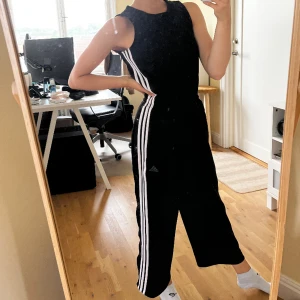 Jumpsuit - En ascool o skön tränings jumpsuit/byxdress från adidas. Har använts flertal gånger men är fortfarande i fantastiskt skick.  Lite kortare i benen. Knappar vid sidorna på benen, dragkedja bak på ryggen och ”gummiband” i midjan så man kan forma den. 🖤🖤