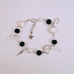 Svart armband med silverdetaljer - Handgjort armband. Svarta glaspärlor, vita akrylpärlor och silverdetaljer (ej äkta). 16 cm i storlek men kan ändras efter önskemål. 