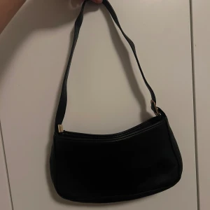 Svart väska - Säljer denna väska då jag inte använder den och ska flytta. Den har inte kommit till användning och är därför i fint skick! Har ett stort fack och ett mindre innerfack. Nypris 249kr
