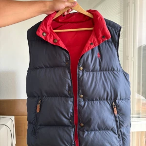 Ralph Lauren väst blå/röd - En vadderad (ej dun) Ralph Lauren väst i bra skick. Går att vända ut o in! Nypris runt 1500kr. Passar mig som är M och 184cm. 