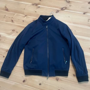 Oscar Jacobson jacka - Harrington/Bomber-jacka från Oscar Jacobson. Storlek 48. En liten skafa i fodret, se sista bilden. Märks inte när den används.