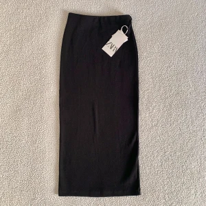 ZARA svart stretchig midikjol - Supersnygg svart midikjol från ZARA. Köpt här på Plick men har inte använts. Ny med tags kvar, utan anmärkningar. Kjolen är rak och har ingen slits, stretchig passform.