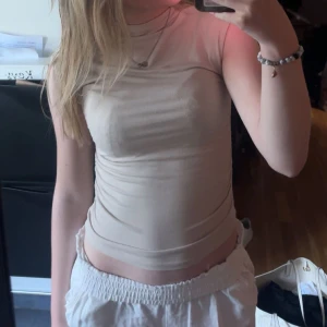 Beige ärmlös topp - En beige ärmlös topp i tight passform. Toppen är enkel och stilren, perfekt för varma sommardagar!!💕