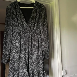 Mönstrad klänning. - Så fin klänning, svart med vita små blommor som mönster. Volang nedtill. Meshtyg i armarna och över klänningen med svart tyg under.❤️Storlek M men lite mindre i storleken.