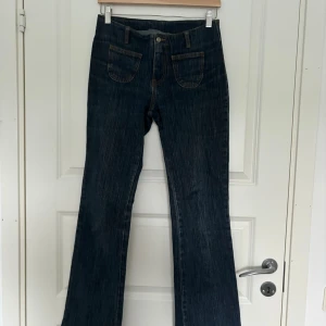 Låga flare jeans - Mörkblåa lågmidjade utsvängda jeans ifrån Brandy Melville i storlek 36. De är något större i midjan på mig så kan även passa en storlek större. Är 168 och de är perfekta längdmässigt i benen för mig! Bra skick.