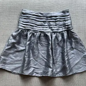 En fin kjol från Kappahl som aldrig använts. Skicket är som nytt. En kall grå färg som är supersnygg och har både dragkedja i sidan samt resor där bak! Kan även användas som topp vilket är snyggt också. Passar även M. Skriv gärna om ni har några frågor!!