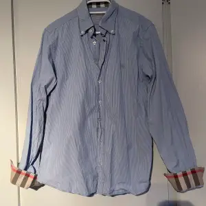Säljer min grymt snygga Burberryskjorta då den dessvärre inte kommer till användning. Ljusblårandigt mönster som är ett måste i sommarens garderob! Tveka inte på att höra av er för fler bilder eller andra frågor. Allt gott!