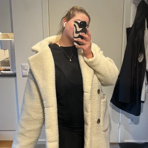 Teddy jacka - Lång varm teddyjacka. Två knäppe med knappar på magen och två fickor.