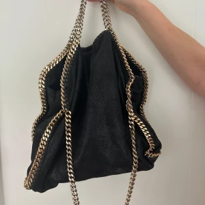 Stella McCartney väska - Stella McCartney väska The Falabella i storlek M.  Nypris 12 000 kr. Mycket fint skick i svart med guldiga detaljer.