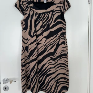 Klänning HM - Använd 1 gång. Storlek 42.  Mörkbeige/svart. Har underklänning.  Längd bak 84 cm 