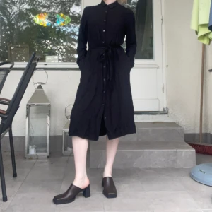 Svart skjortklänning - Svart midilång skjortklänning från Uniqlo. 100% viskos så den är otroligt sval och skön på sommaren. Dessutom har den fickor(!!!) Sista knapphålet på kjolen är skadat (se bild 3) 🫶🏻