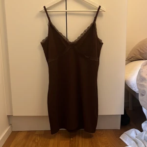 Klänning med spets - Brun klänning med spetsdetalj! Justerbara band och ribbat material.