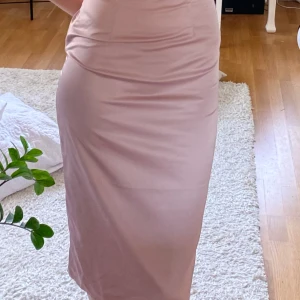 Rosa midiklänning  - Gullig rosa midiklänning från Na-kd i storlek 32. Använd fåtal gånger, i fint skick. Obs jag håller inte in klänningen i midjan jag blir bara obekväm när jag ska ta bilder och vet inte var jag ska ha mina händer hah.