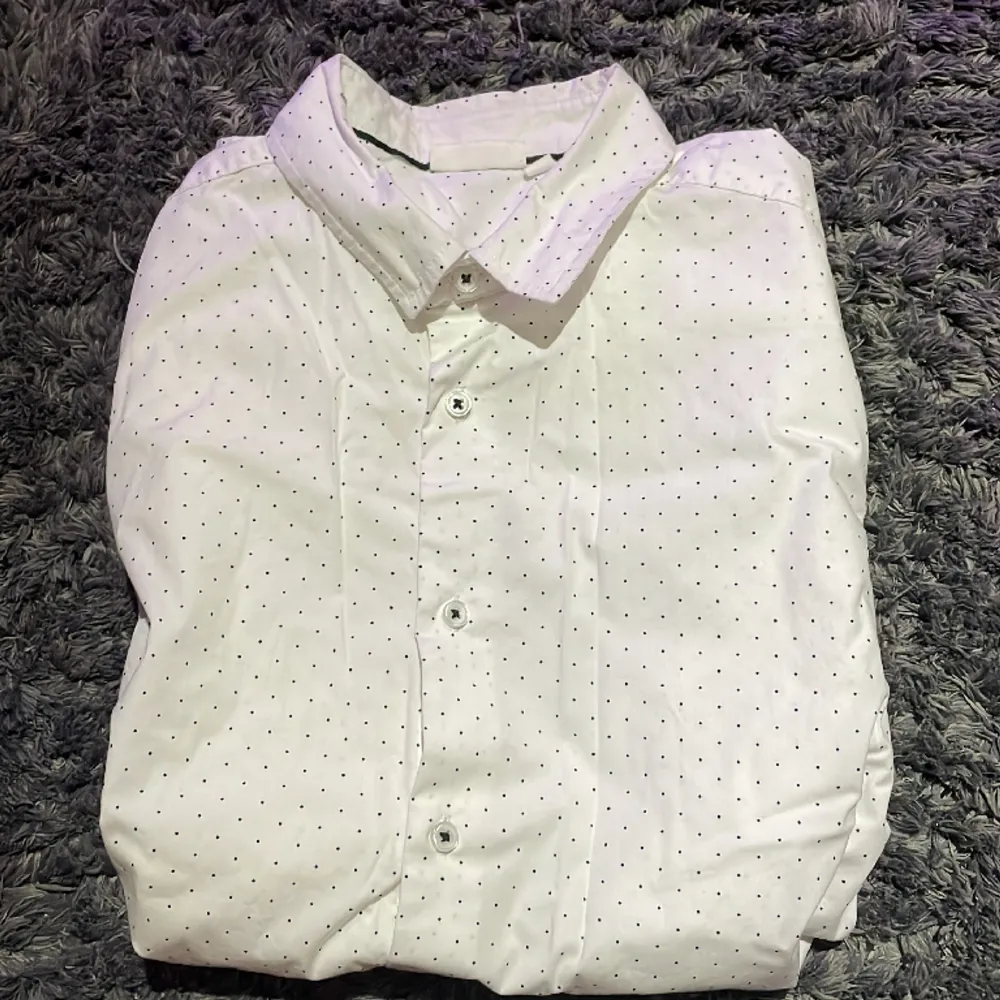Skjorta från Kappahl i färgen vit med svarta prickar. Använd endast få gånger och är i ett mycket bra skick. Inga tecken på användning alls.. Skjortor.