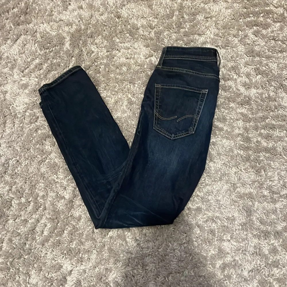 Mörkblå jeans från Jack and Jones i modellen regular/clark. Storlek 28/32. Nypris runt 600 och i bra skick (7/10 då loggan där bak är av på mitten).Hör av er vid prisförhandling, fler bilder, mått eller  andra tankar så kommer svar snabbt💫. Jeans & Byxor.