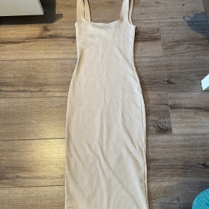 Lång ribbad klänning  - Lång ribbad ljusrosa/beige klänning. Kroppad men bekväm. 