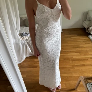 Vit långklänning - Vit långklänning med blommönster. Klänningen är tajt men stretchig passform. Liten/normal i storlek.  Som referens för längd så är jag 178cm, alltså är klänningen lång.  