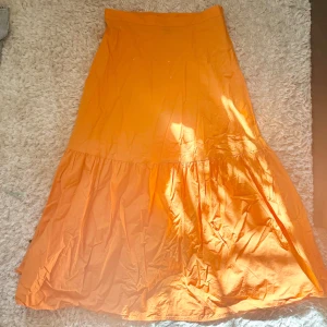 Orange långkjol -  Kjol i orange färg! Köpt på Lindex men slutsåld. Lite för kort på mig som är 176 men tror den passar perfekt på någon mellan 160-170!