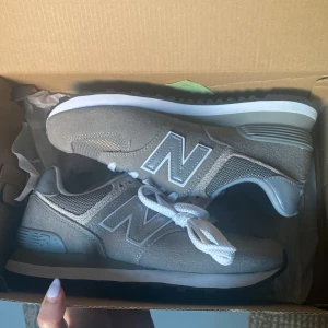 New Balance 574 - Modell: New Balance Classic 574 Storlek: 38,5 Färg: Grå Skick: Oanvända Nypris: 1250kr  Fina new balance skor säljes pga för små i storleken. Jag är vanligtvis en 38/39. Köptes för två år sen men legat i lådan sen dess och är helt oanvända.   