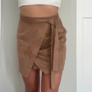 Omlottkjol River Island  - Omlottkjol i mocka-imitation från River island  Storlek 34  Har dragkedja i bak + ”skärp”liknande detaljer 