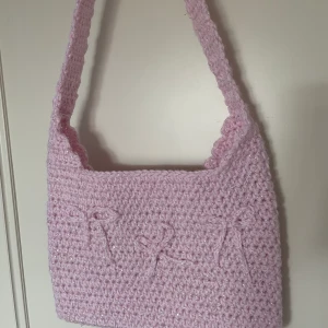 Söt virkad väska  - Handvirkad väska gjort på rosa glittrigt garn. Små rosetter är påsydda. 
