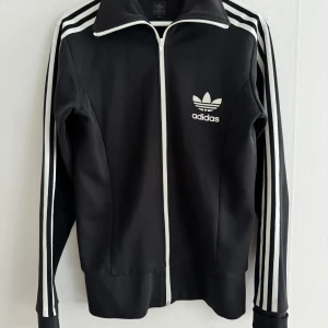 Adidas tröja vintage - Säljer en snygg adidas tracksuit i svart, vintage med långa kragar. I storlek small. I fint använt skick. Köpt 2004 om jag inte minns fel, modellen gavs ut som limited edition. 