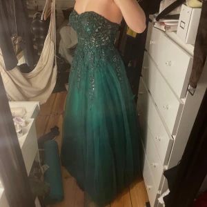 Mörkgrön balklänning - Helt ny mörkgrön balklänning som jag tyvärr måste sälja för att den inte riktigt passade mig. Jag är 172cm och den går precis ner till marken. 
